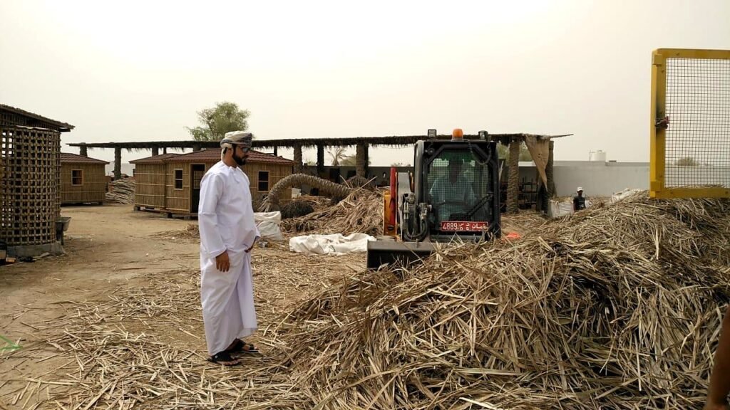 Industrial Applications Handling yard with palm-frond stock and cabins built from palm midribs
